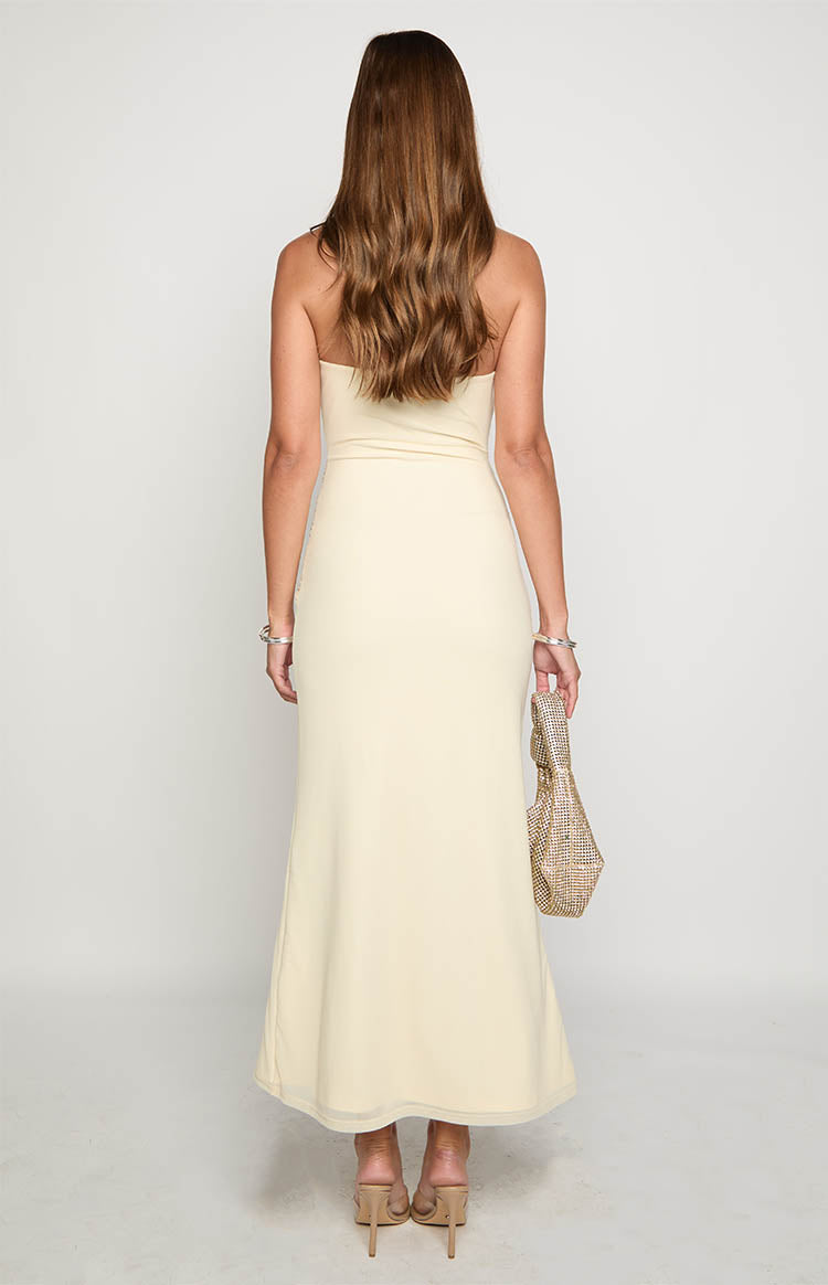 Blonde model wearing a strapless cream mesh maxi dress with ruched details through the bodice