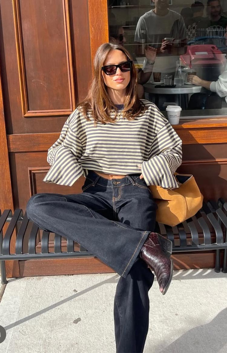 brunette model wearing a navy and beige striped long sleeve top paired with a light wash denim mini skort