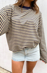 brunette model wearing a light wash denim mini skirt paired with a long sleeve blue and cream stripe top