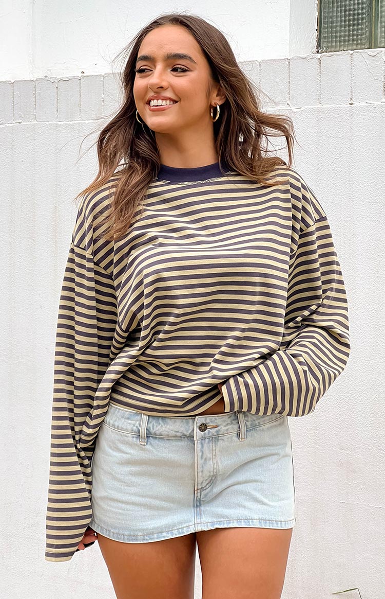 brunette model wearing a navy and beige striped long sleeve top paired with a light wash denim mini skort