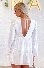 Girl wearing a white long sleeve mini dress with an open back and adjustable tie detail