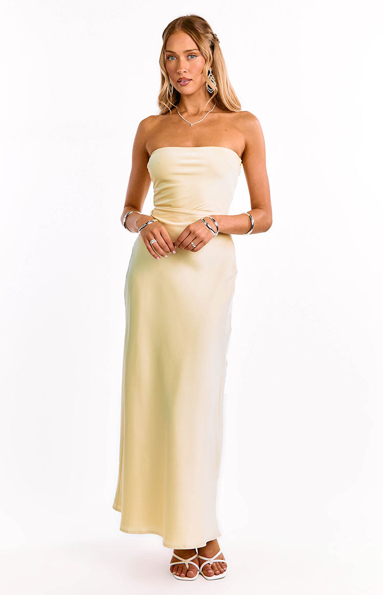 A model in a yellow strapless maxi dress with an elegant straight neckline. This sophisticated formal dress features a sleek column silhouette. An ideal choice for a wedding guest or graduation ceremony.