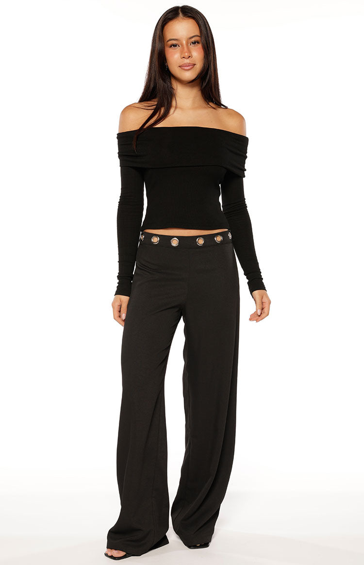 Woman wearing a black ribbed off-shoulder long sleeve top with dark trousers a versatile staple for a Fall wardrobe