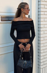 Woman wearing a black ribbed off-shoulder long sleeve top with dark trousers a versatile staple for a Fall wardrobe