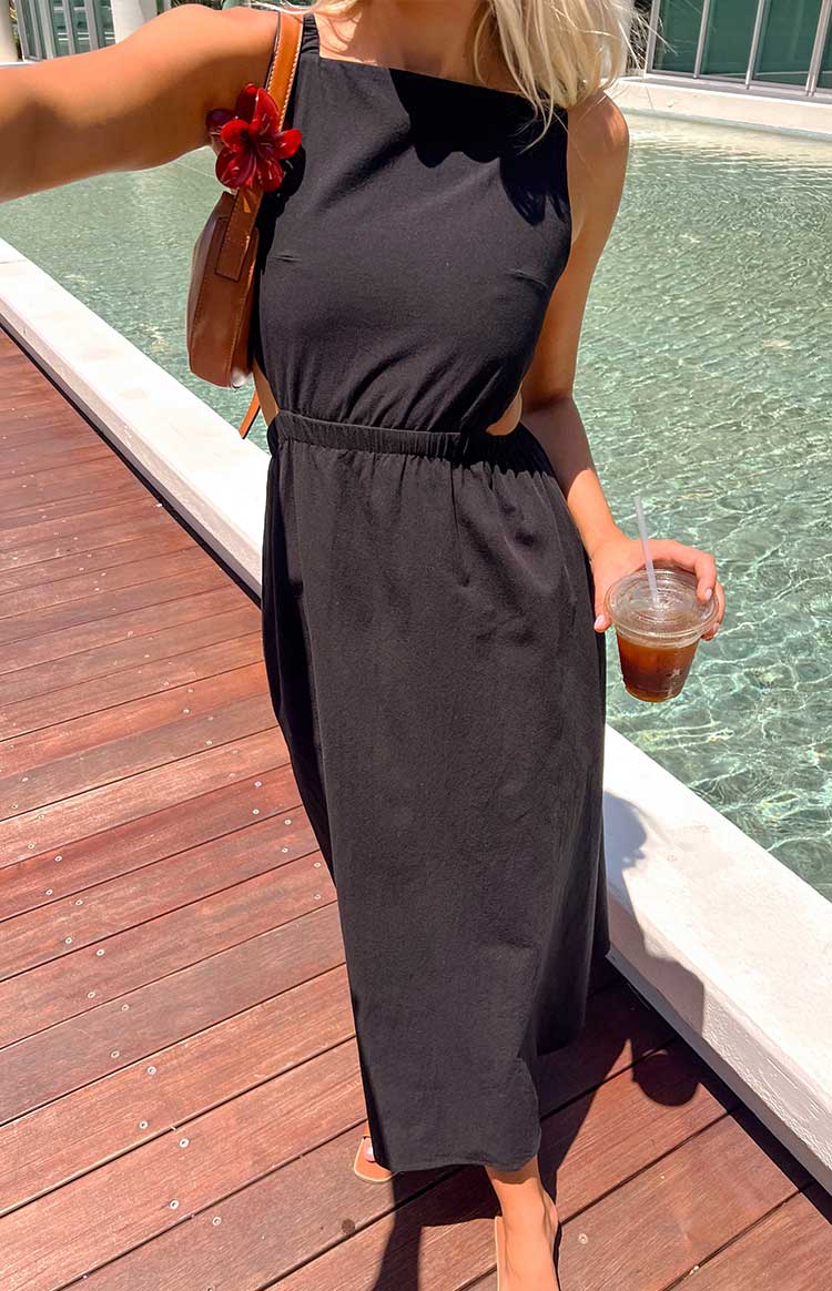 a black maxi dress worn by a blonde girl with a brown handbag