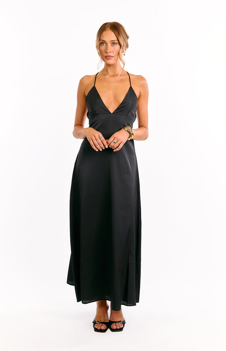 Model wears a black halter neck maxi dress with waist cut outs. This flowy evening gown features a babydoll silhouette. A unique choice for a formal event or a cocktail party.
