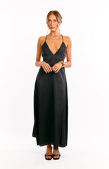 Model wears a black halter neck maxi dress with waist cut outs. This flowy evening gown features a babydoll silhouette. A unique choice for a formal event or a cocktail party.
