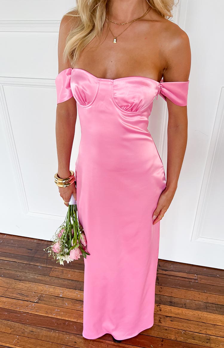 Blonde model wearing a pink satin maxi dress with off shoulder straps and a structured bust