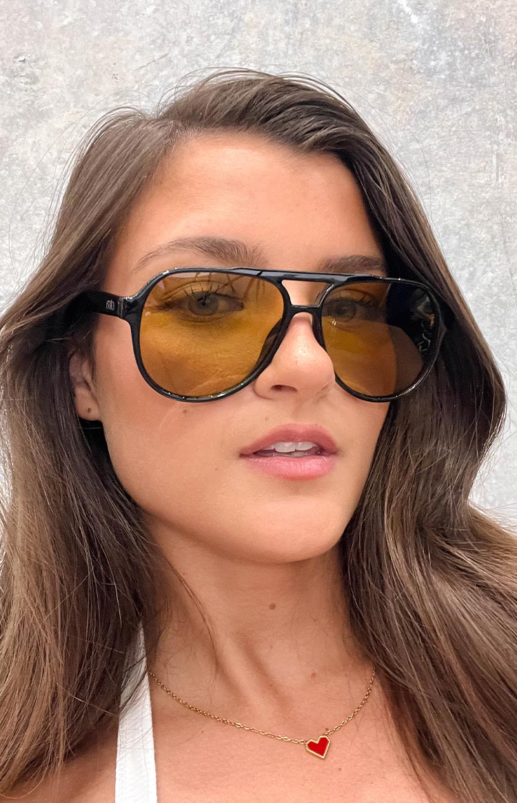 girl wearing retro style aviator sunnies with a black frame and olive lenses