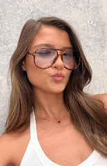 brunette model wearing brown tortoiseshell frame aviator sunnies with light blue grey lenses