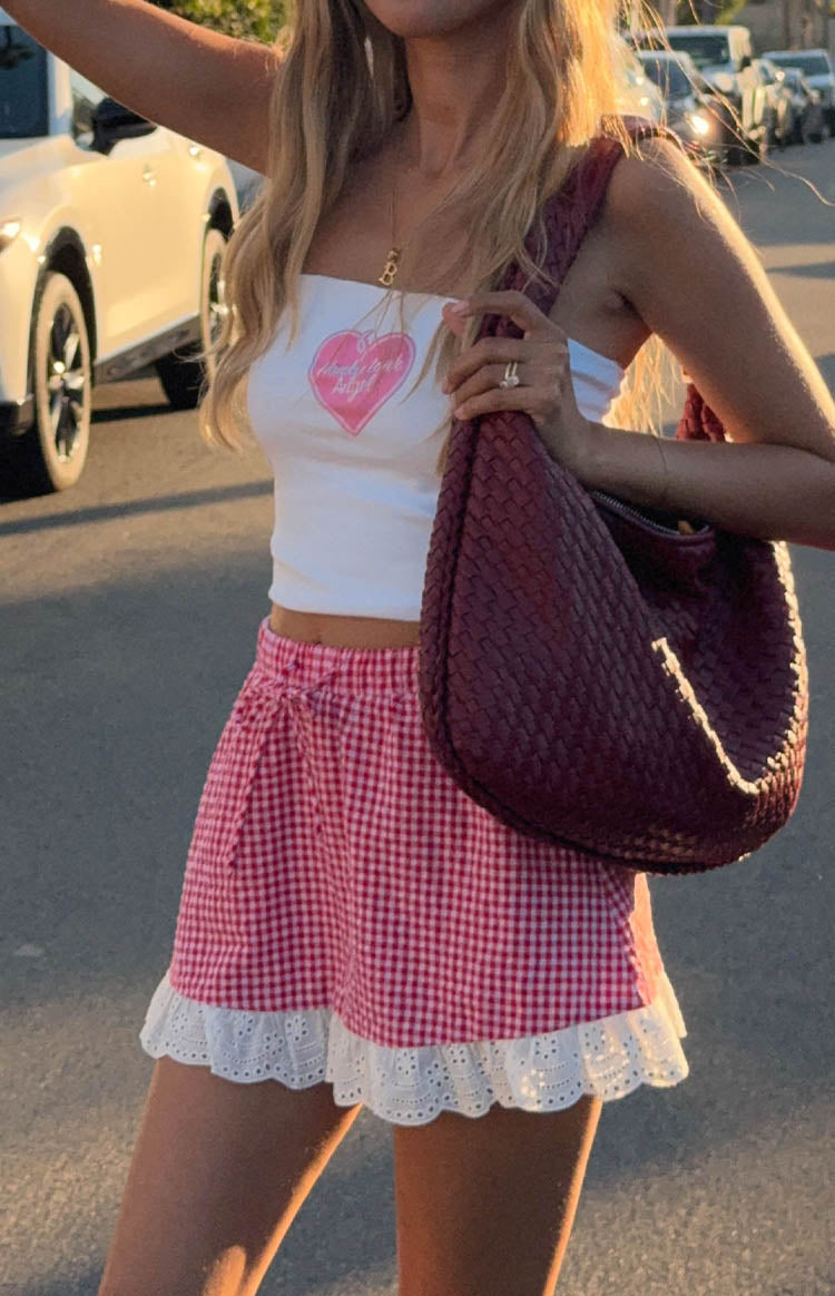 model wearing a red gingham mini skirt with white ruffle details and white tube top