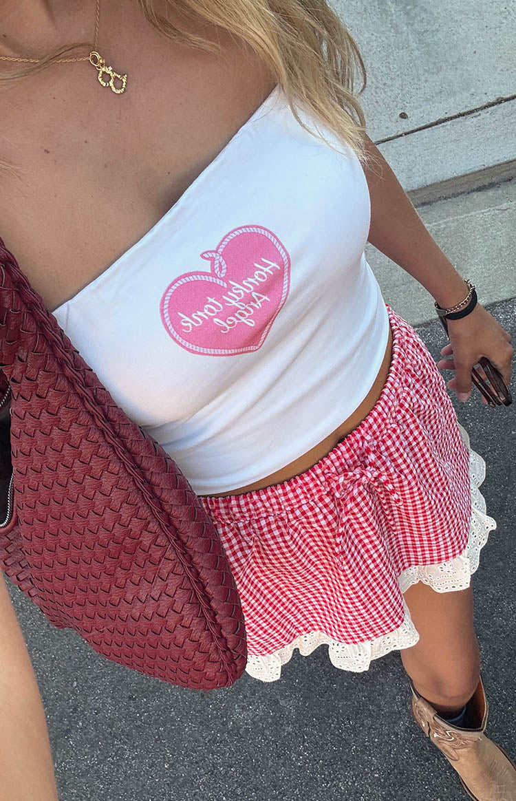 girl wearing a red gingham mini skirt with white ruffle details paired with a white tube top