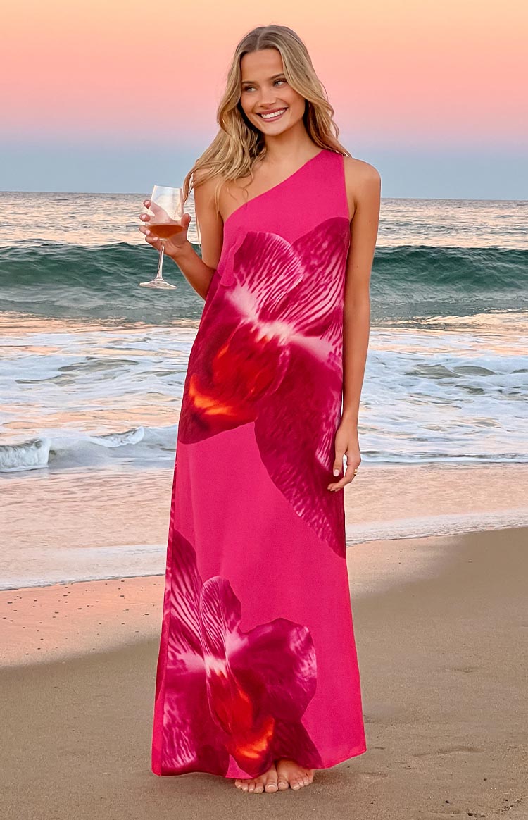 A striking fuchsia one-shoulder maxi dress with oversized red orchid prints- perfect for a tropical formal event or beachside gathering.