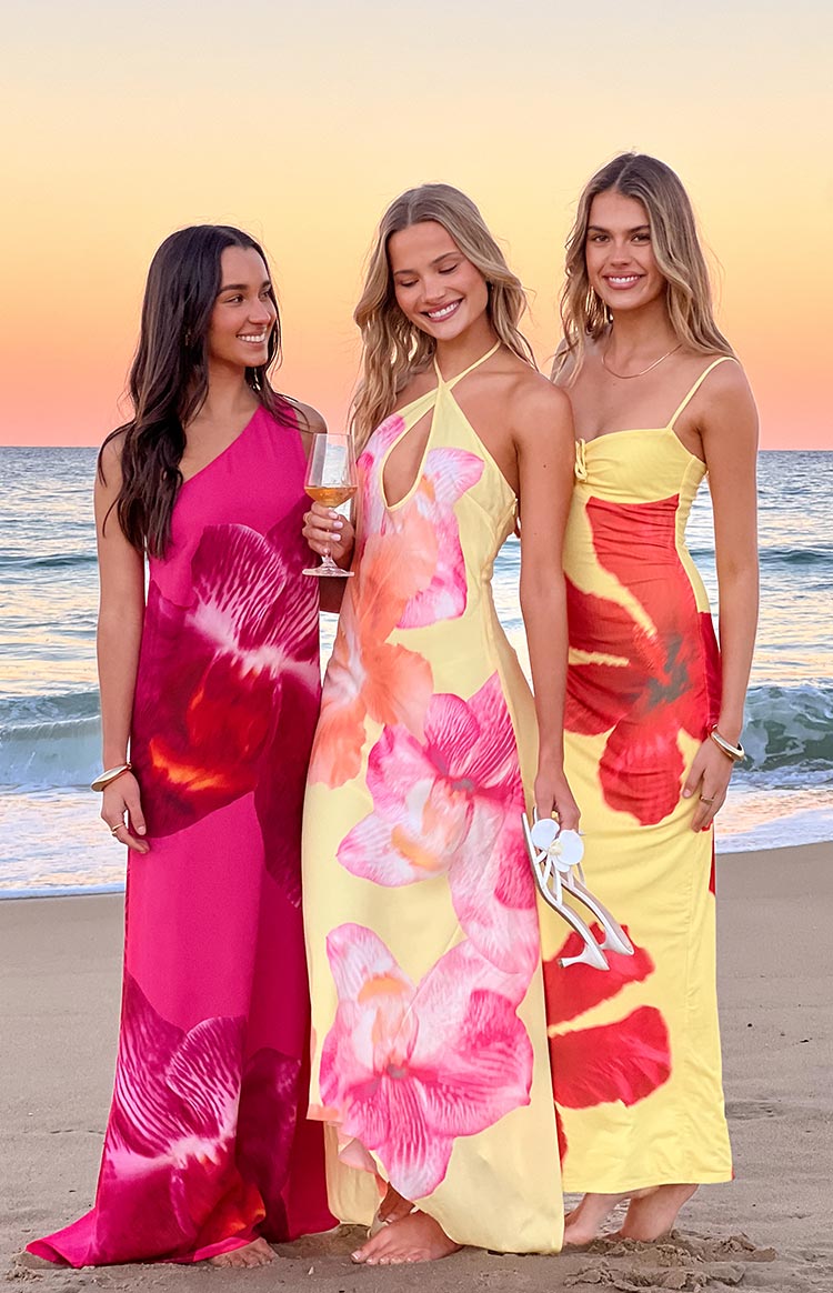 A striking fuchsia one-shoulder maxi dress with oversized red orchid prints- perfect for a tropical formal event or beachside gathering.