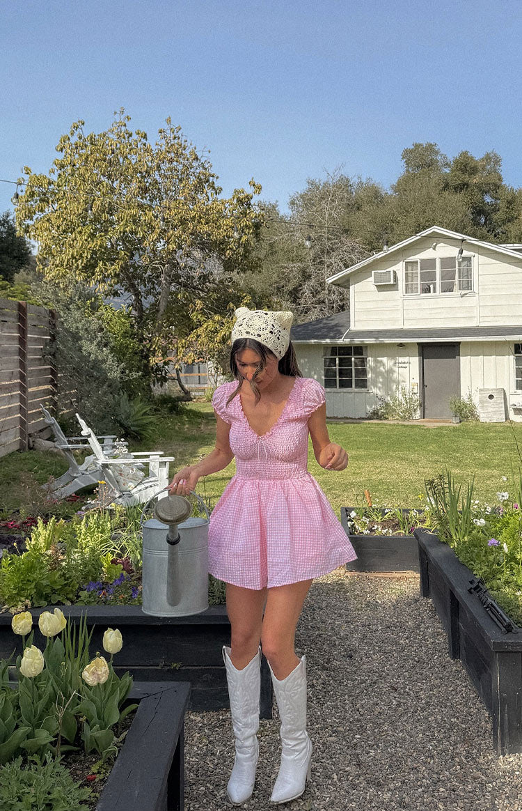 Model is wearing a pink gingham playsuit and gold jewellery.