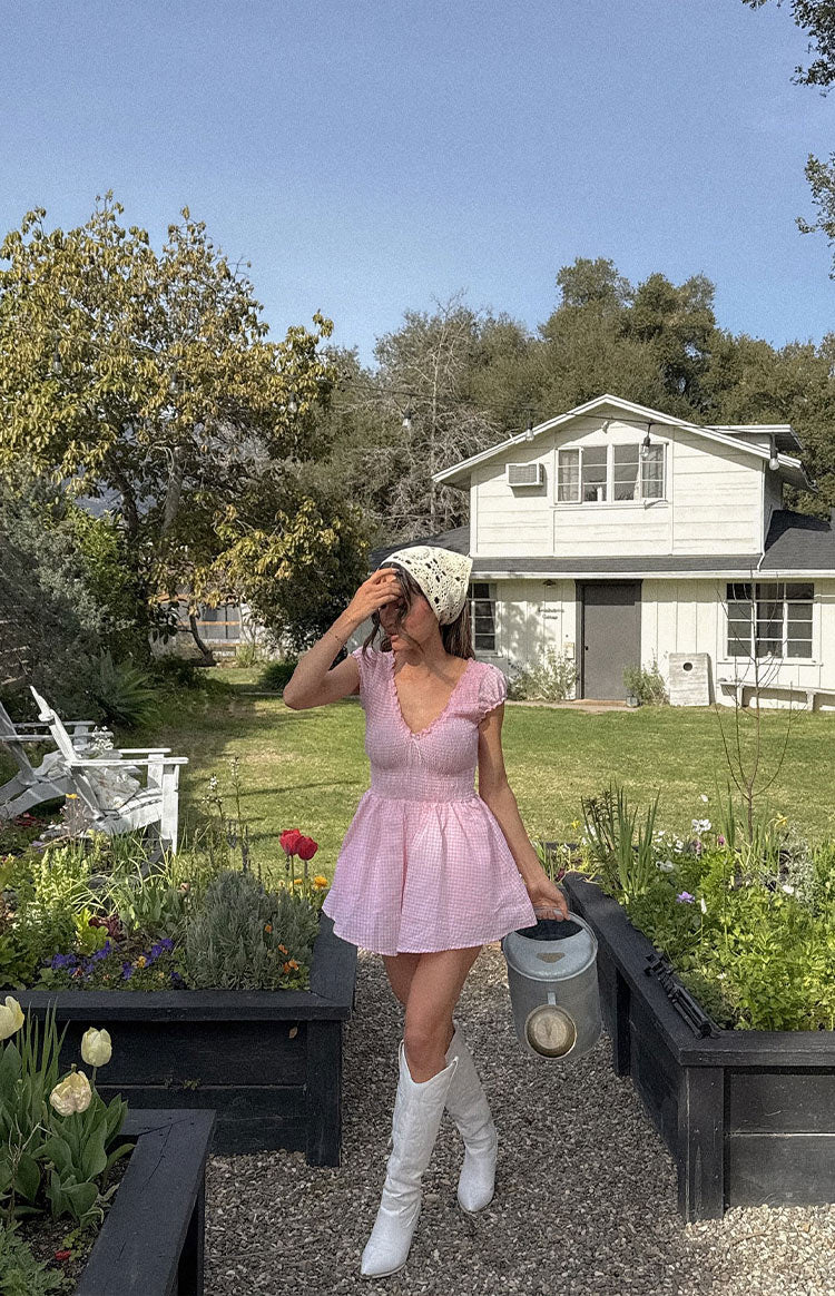 Model is wearing a pink gingham playsuit and gold jewellery.