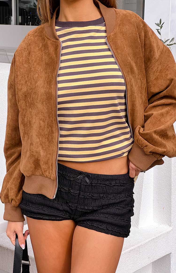 Model wears a tan suedette bomber jacket with cuffed sleeves for a casual everyday outfit.