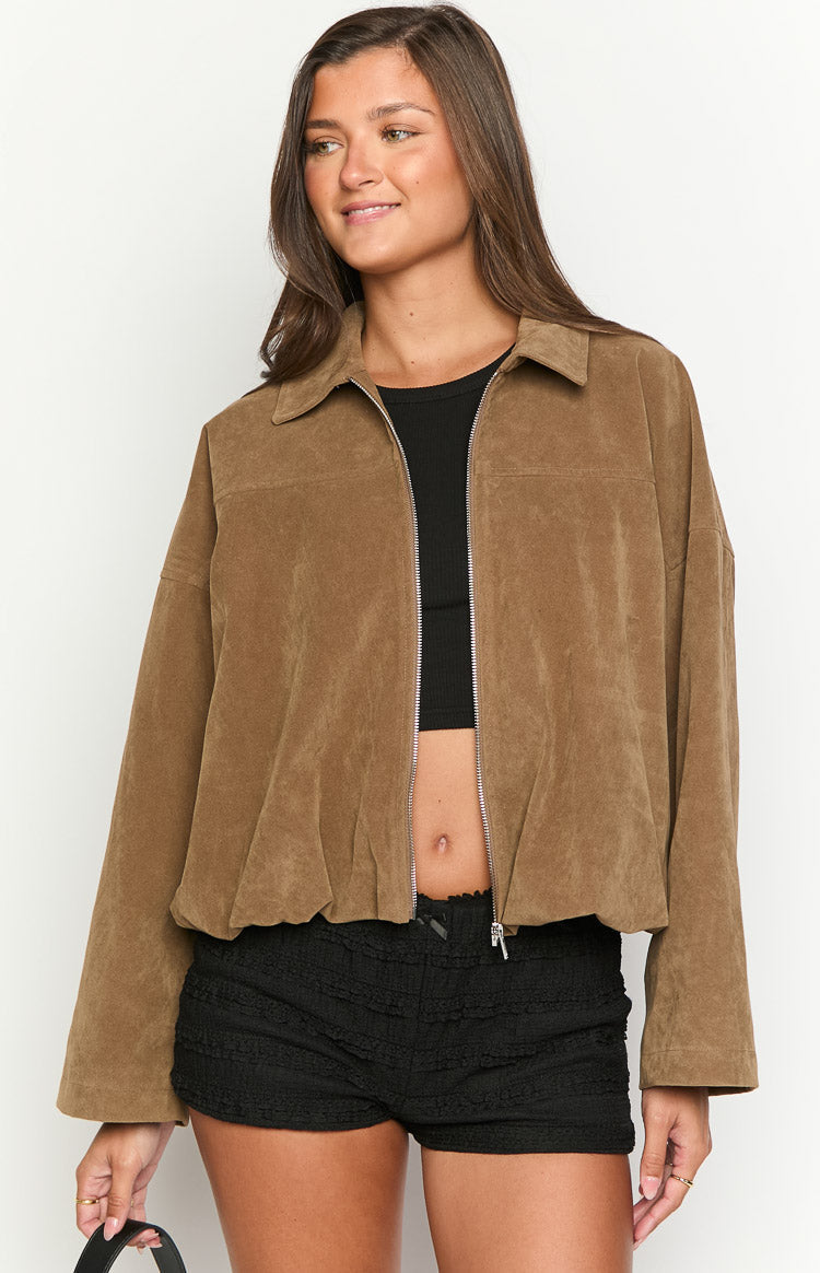 Close-up of a model wearing an open brown suede-like or corduroy jacket over a black ribbed top