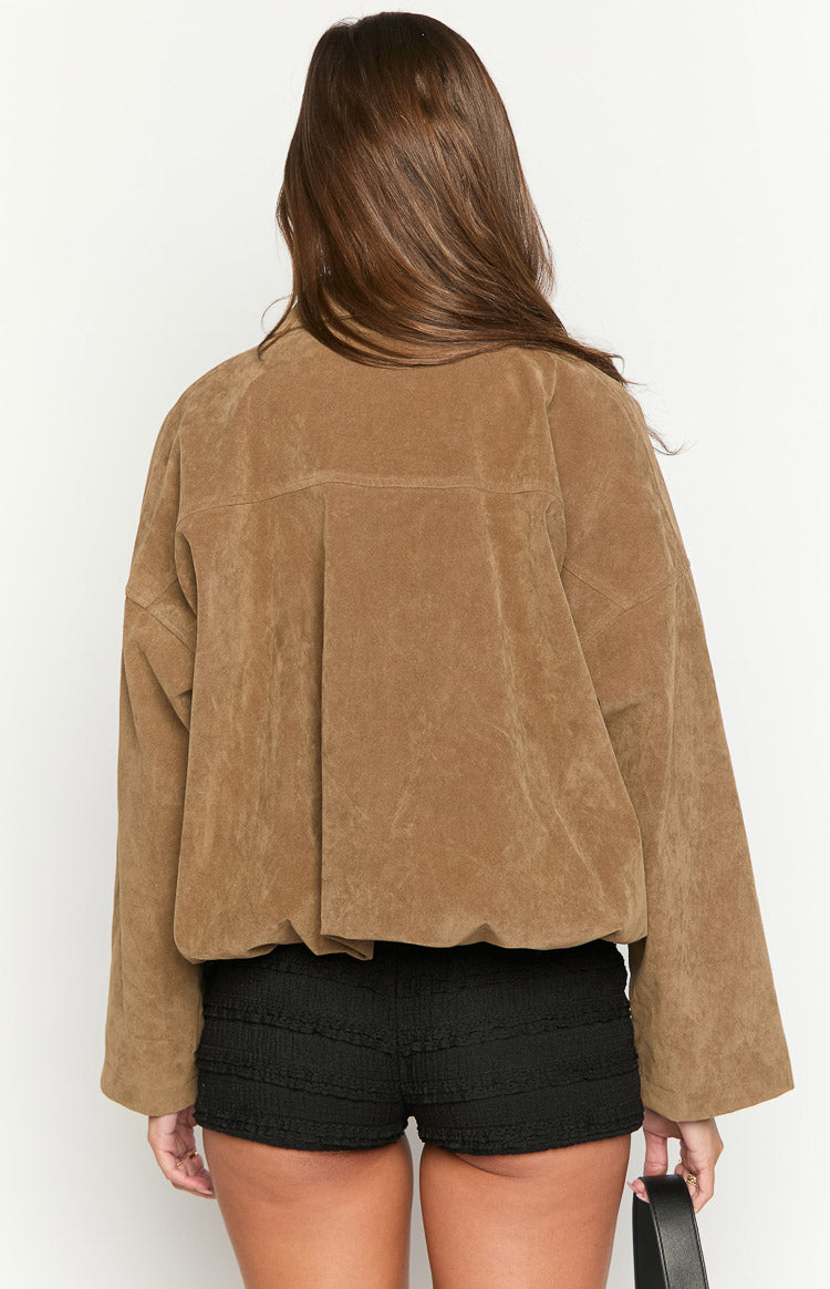 Close-up of a model wearing an open brown suede-like or corduroy jacket over a black ribbed top