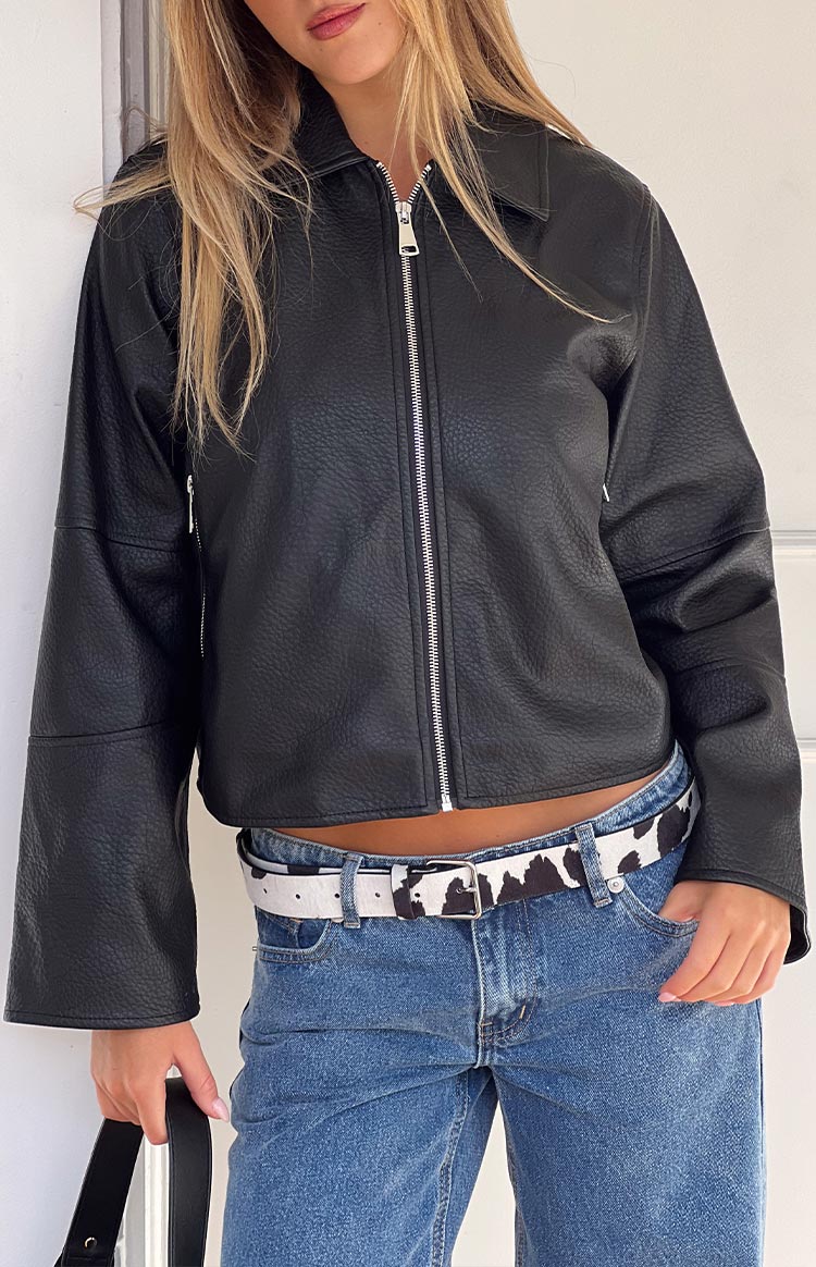 Blonde model wearing a black PU leather jacket with an oversized silver zip closure