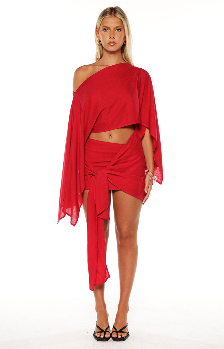 Close up of a girl wearing a red mini dress with an asymmetric sleeve and wrap detail at te skirt. The perfect choice for a christmas celebration or party!