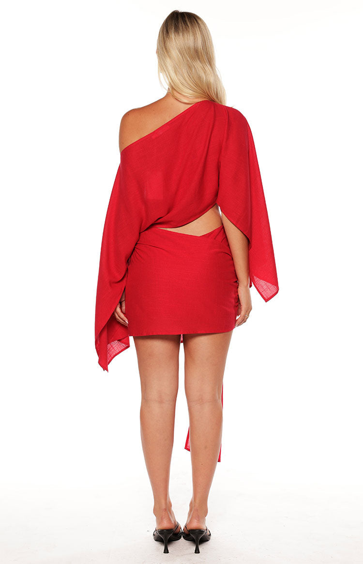 Close up of a girl wearing a red mini dress with an asymmetric sleeve and wrap detail at te skirt. The perfect choice for a christmas celebration or party!