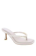 A pair of ivory thong heels featuring pearl embellishments a square toe and a low block heel.