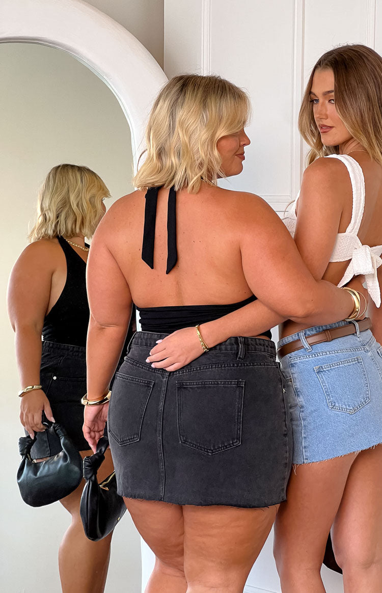 blonde model wearing a black denim mini skirt paired with a white plain halter neck top and gold jewellery