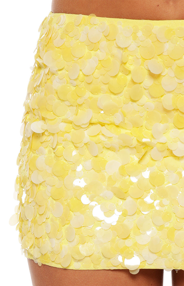 Woman in a sparkling yellow sequin mini skirt and a white halter top a fun outfit for a birthday party or celebration