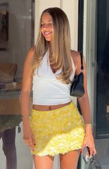 Woman in a sparkling yellow sequin mini skirt and a white halter top a fun outfit for a birthday party or celebration