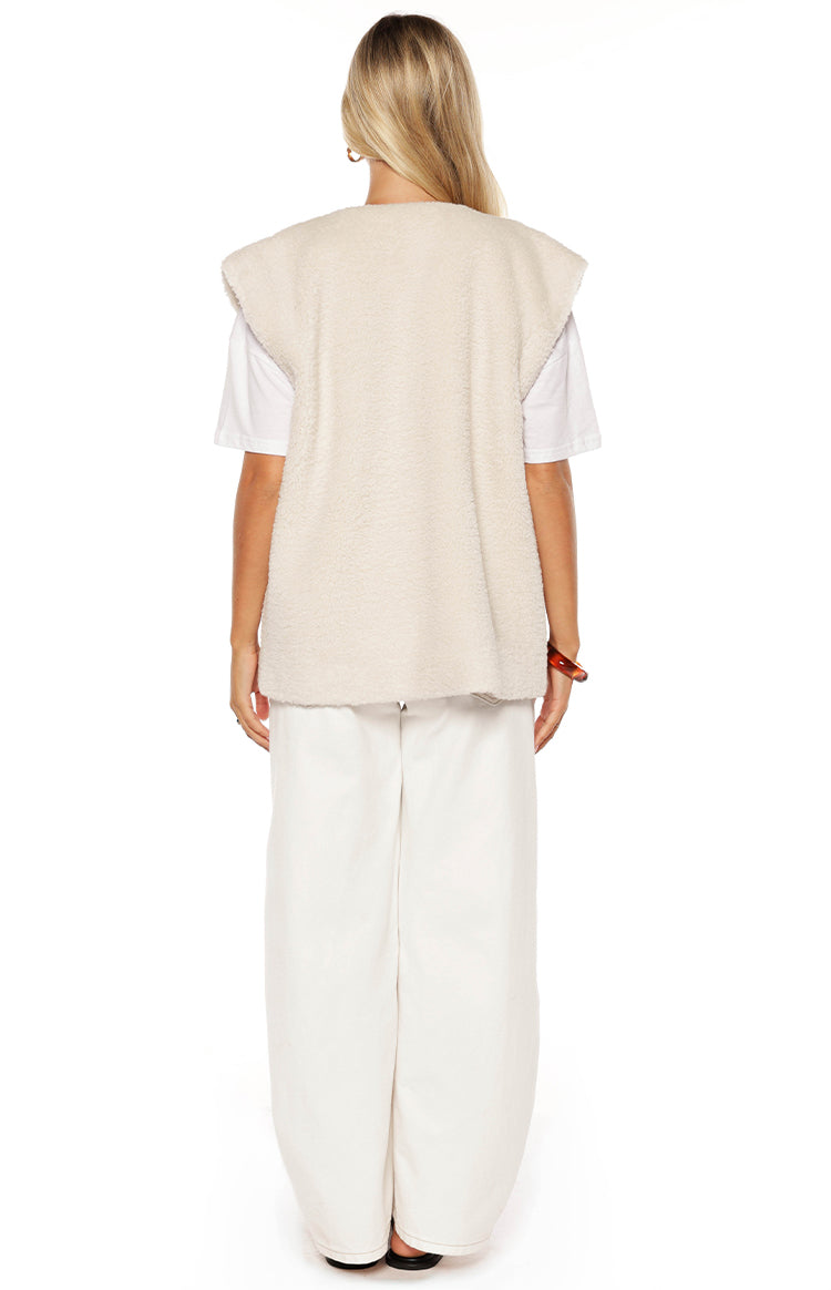 Girl in a soft cream fleece vest and white pants a trendy and cozy outfit ideal for a casual Spring day out