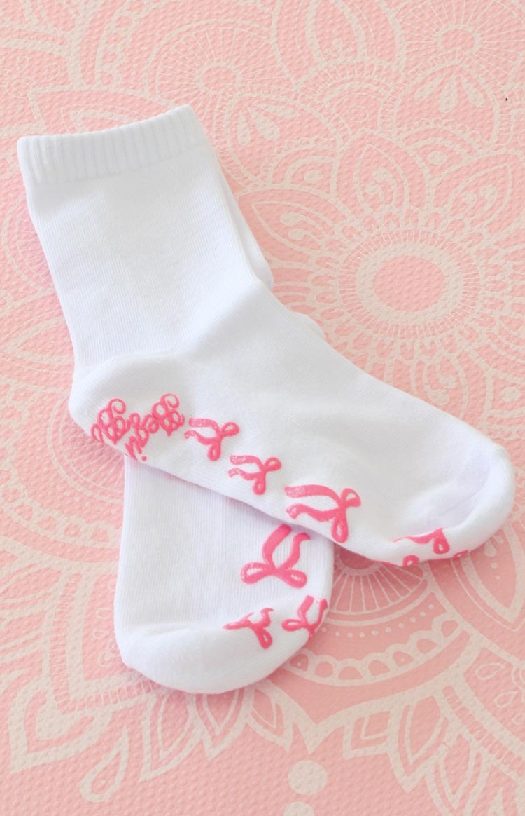 white yoga socks with pink bow shaped grips on the bottom and a graphic 'beginning boutique' grip