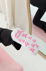 white yoga socks with pink bow shaped grips on the bottom and a graphic 'beginning boutique' grip