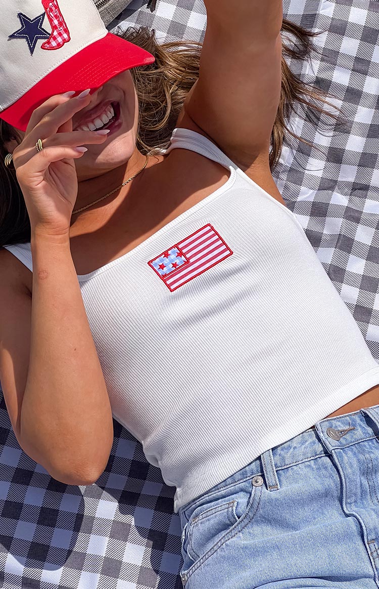 Model wearing a white sleeveless tank top with a red and blue patch graphic on the front