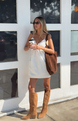 Girl in a white slip mini dress styled with cowboy boots a flirty outfit for a Spring festival or brunch