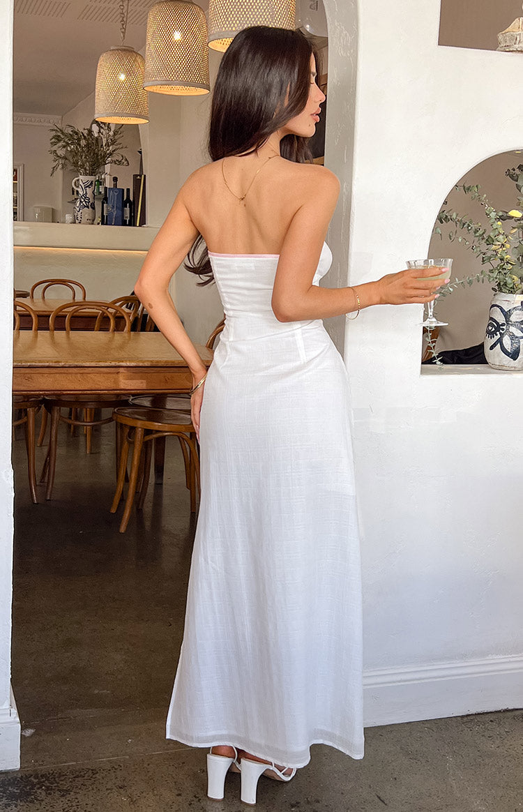 Back of girl wearing a white strapless maxi dress with a drink in her hand.