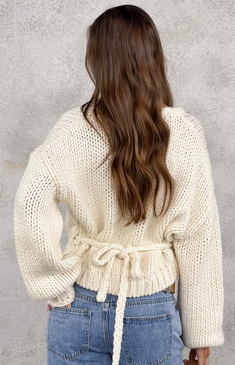 Model wearing a cream chunky knit wrap sweater with a V-neck
