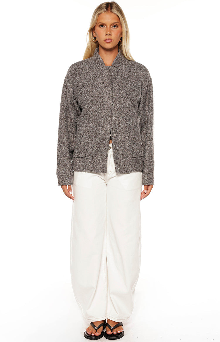 Smiling girl wearing a grey boucle bomber jacket over a crop top and white jeans a cozy look for a cool Autumn day