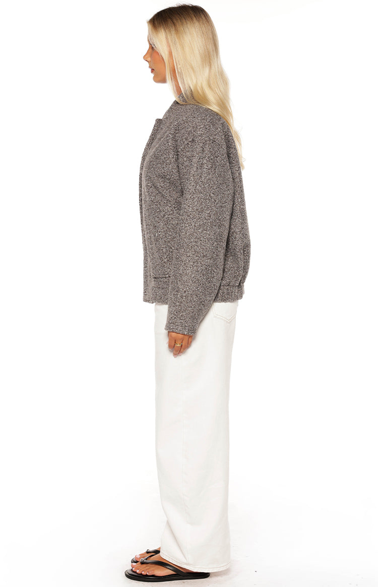 Smiling girl wearing a grey boucle bomber jacket over a crop top and white jeans a cozy look for a cool Autumn day