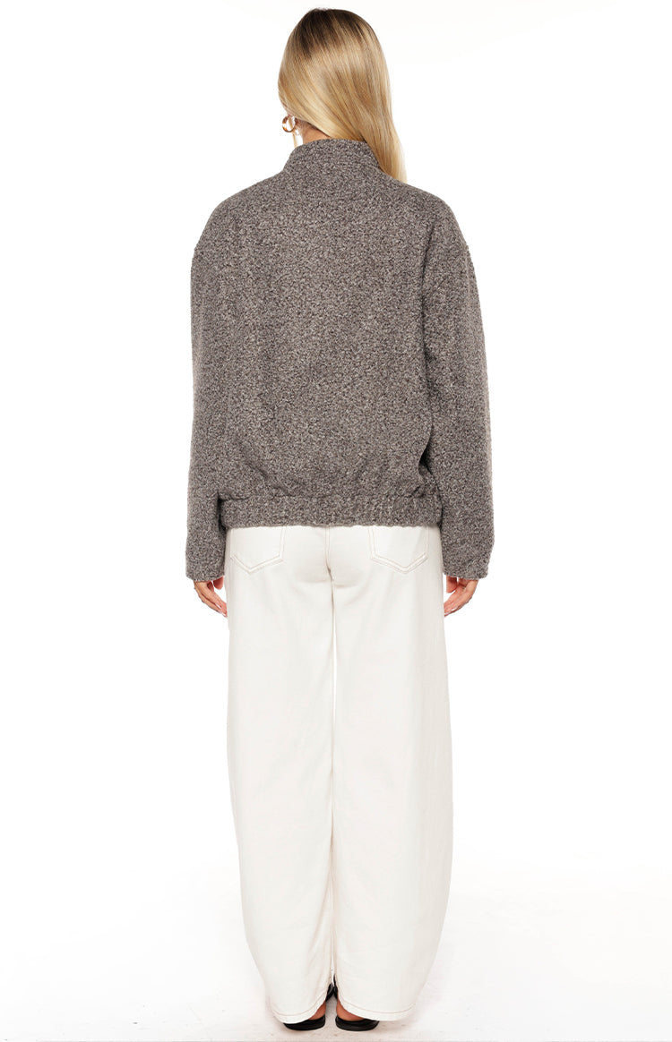 Smiling girl wearing a grey boucle bomber jacket over a crop top and white jeans a cozy look for a cool Autumn day