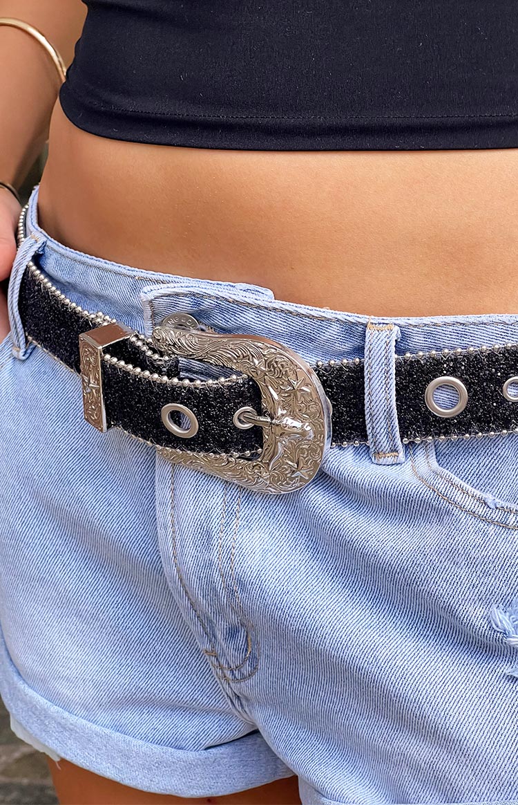 girl wearing light blue denim shorts paired with a black and silver sparkle belt and a black top