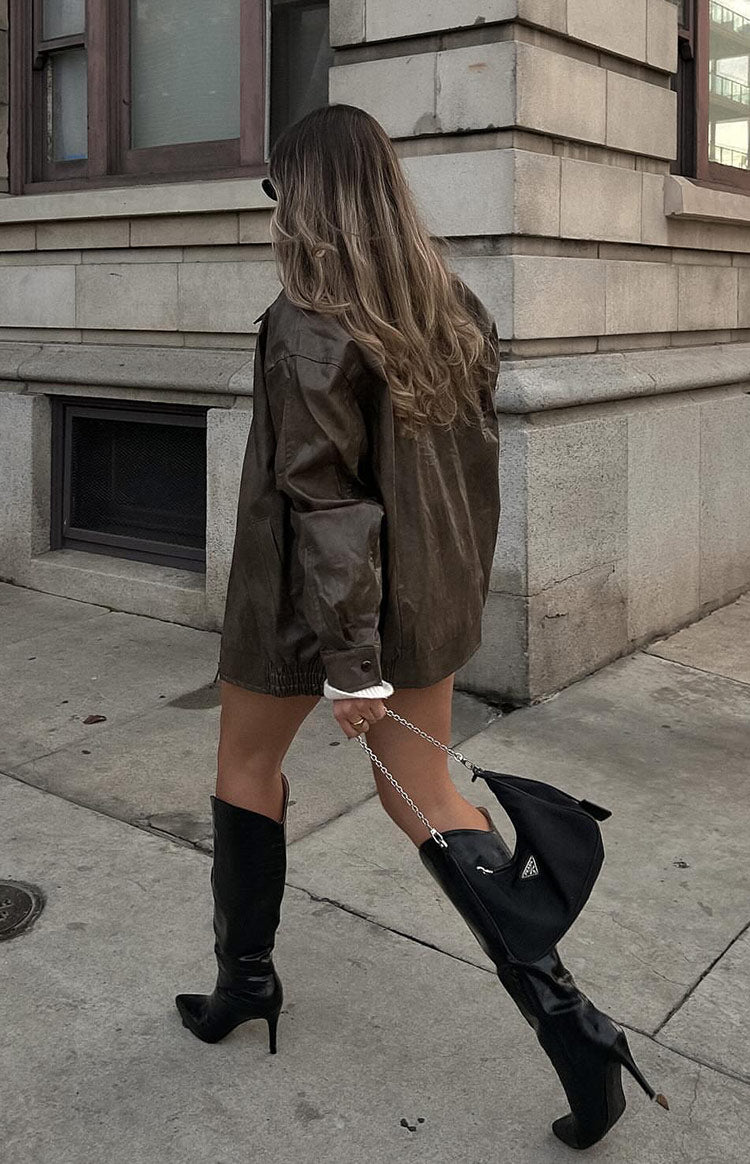 Faux leather oversized brown bomber jacket. Worn by model walking the street.