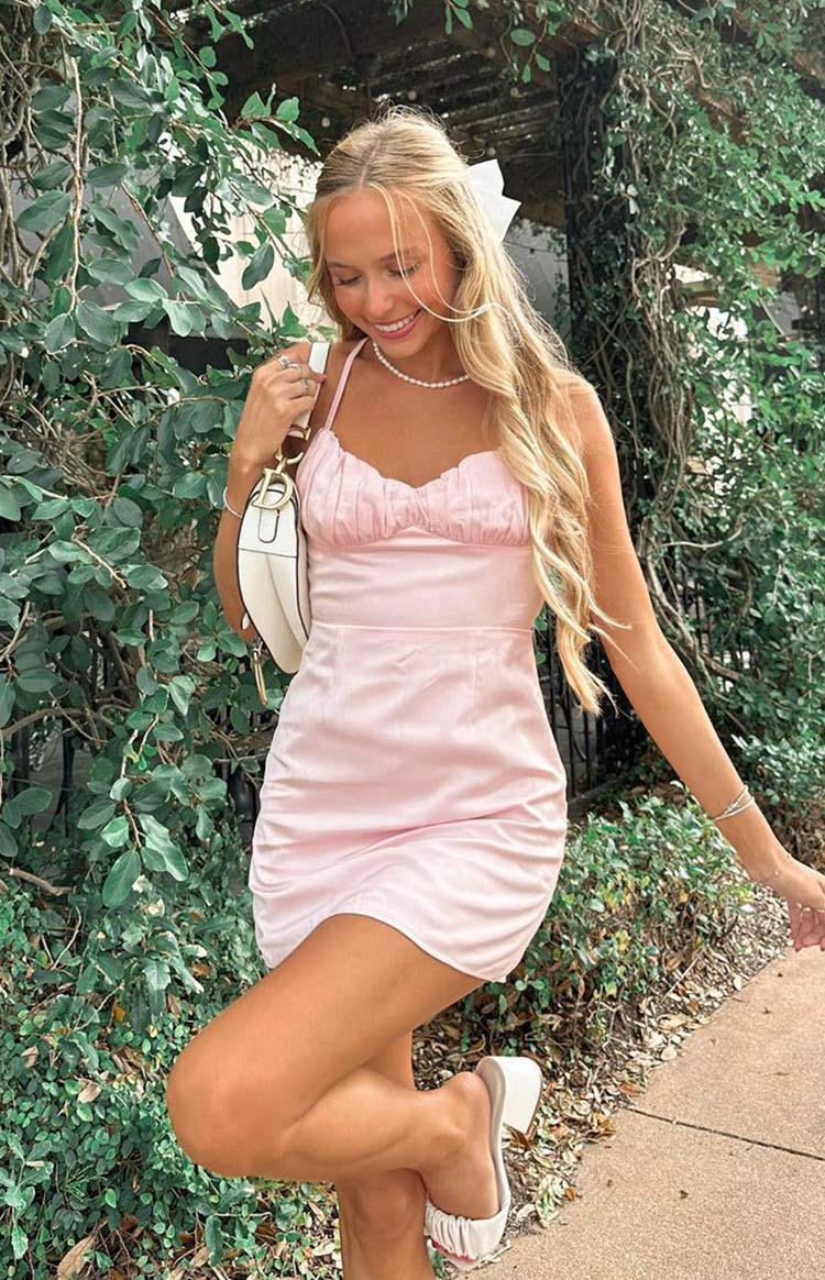 Light pink satin mini cocktail dress with gathered detailing on bust and thin straps styled on blonde model.